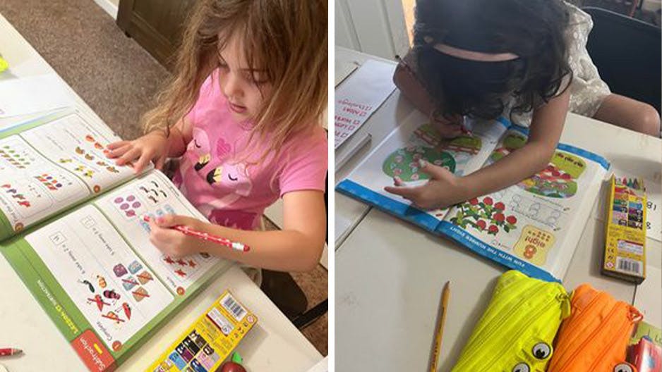 Two kindergarten girls homeschool with Reading Eggs workbooks.