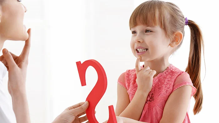 Image of an adult teaching a girl how to enunciate sounds